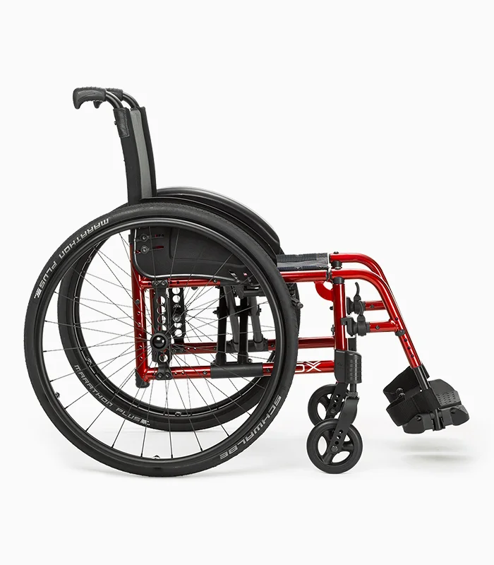 Ki Mobility Catalyst wheelchair with red frame, side view.
