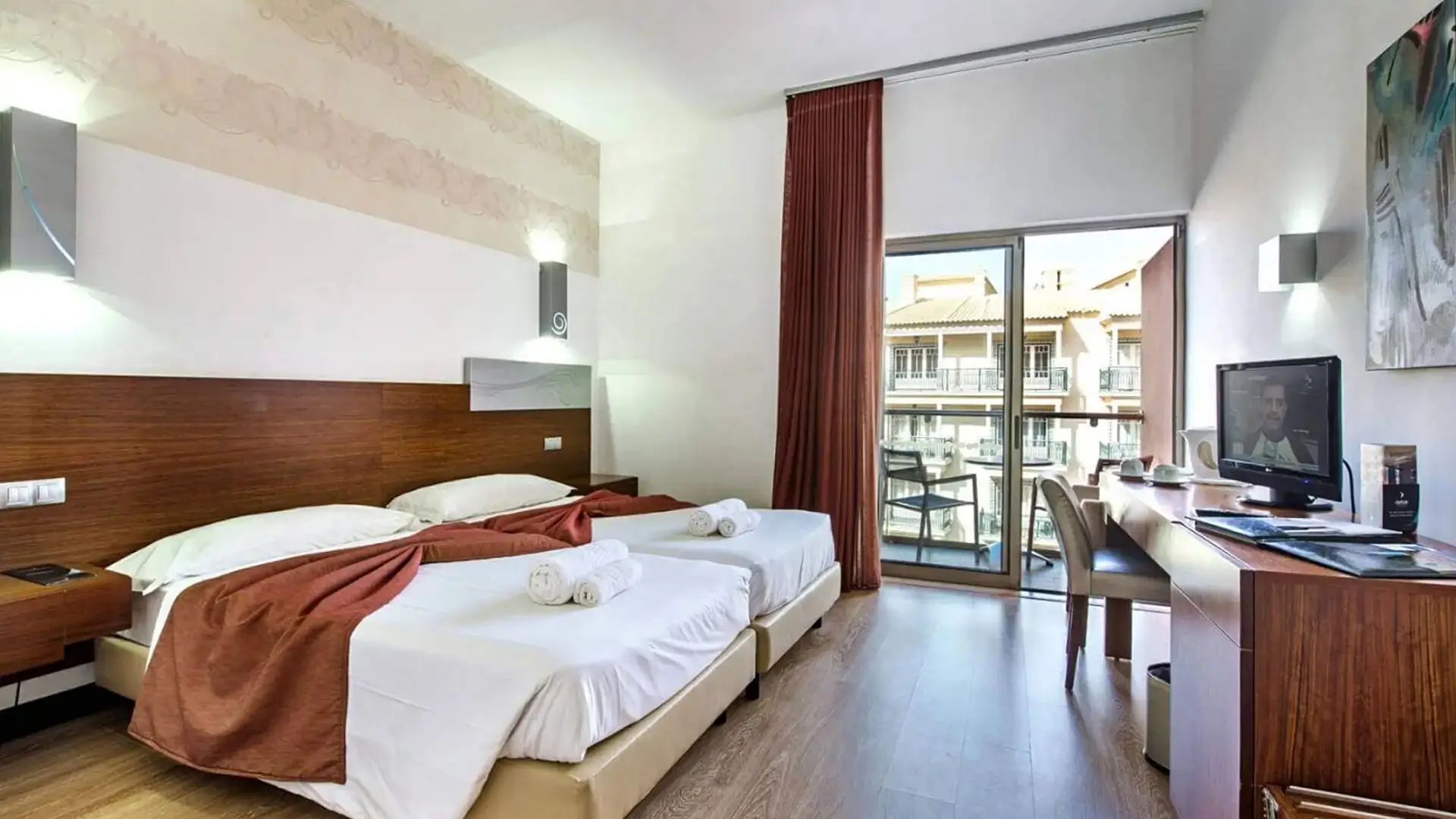 Hotel room with two beds and balcony view.