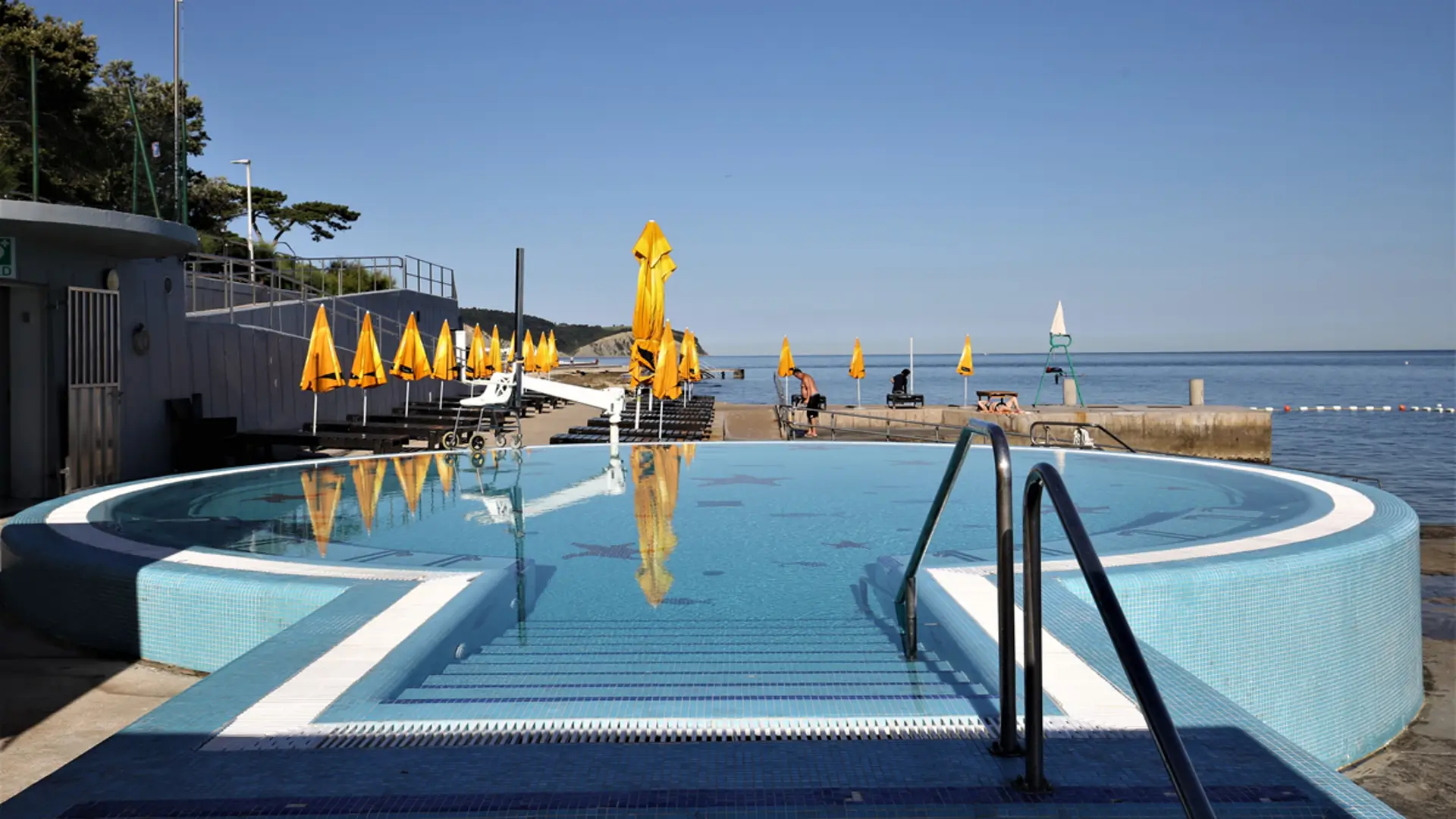 Round pool with wide steps near beach umbrellas.
