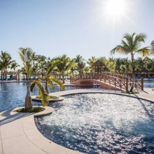 Resort pool with bridge and palm trees.