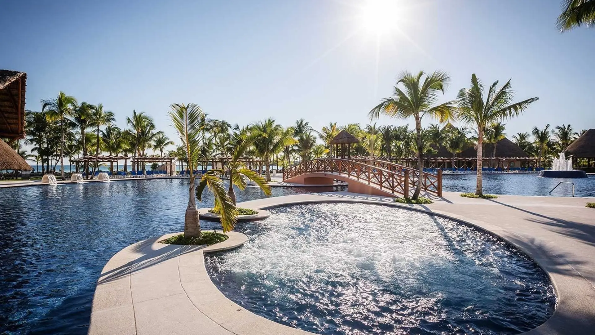 Resort pool with bridge and palm trees.