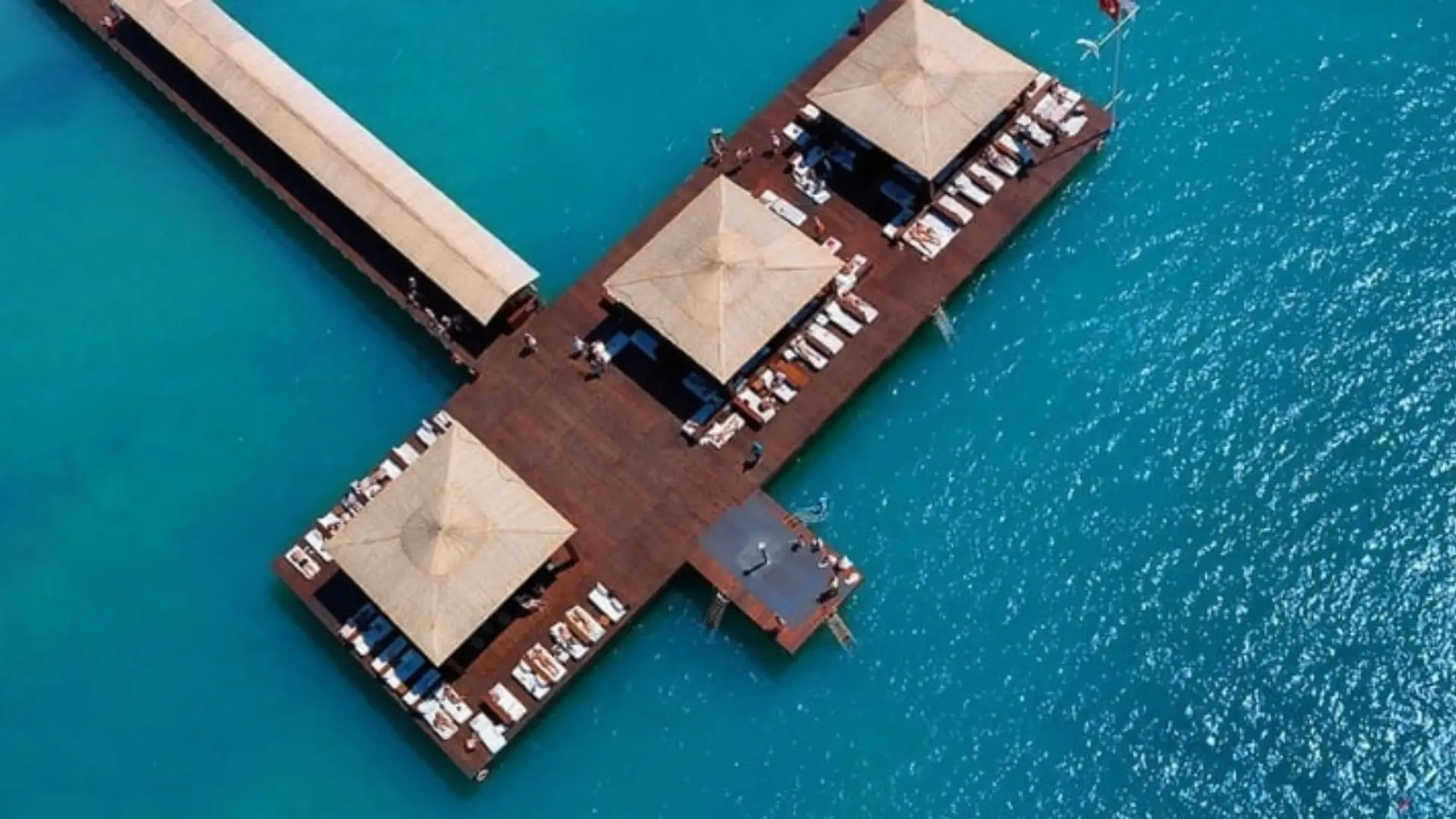 Aerial view of pier with umbrellas over water.