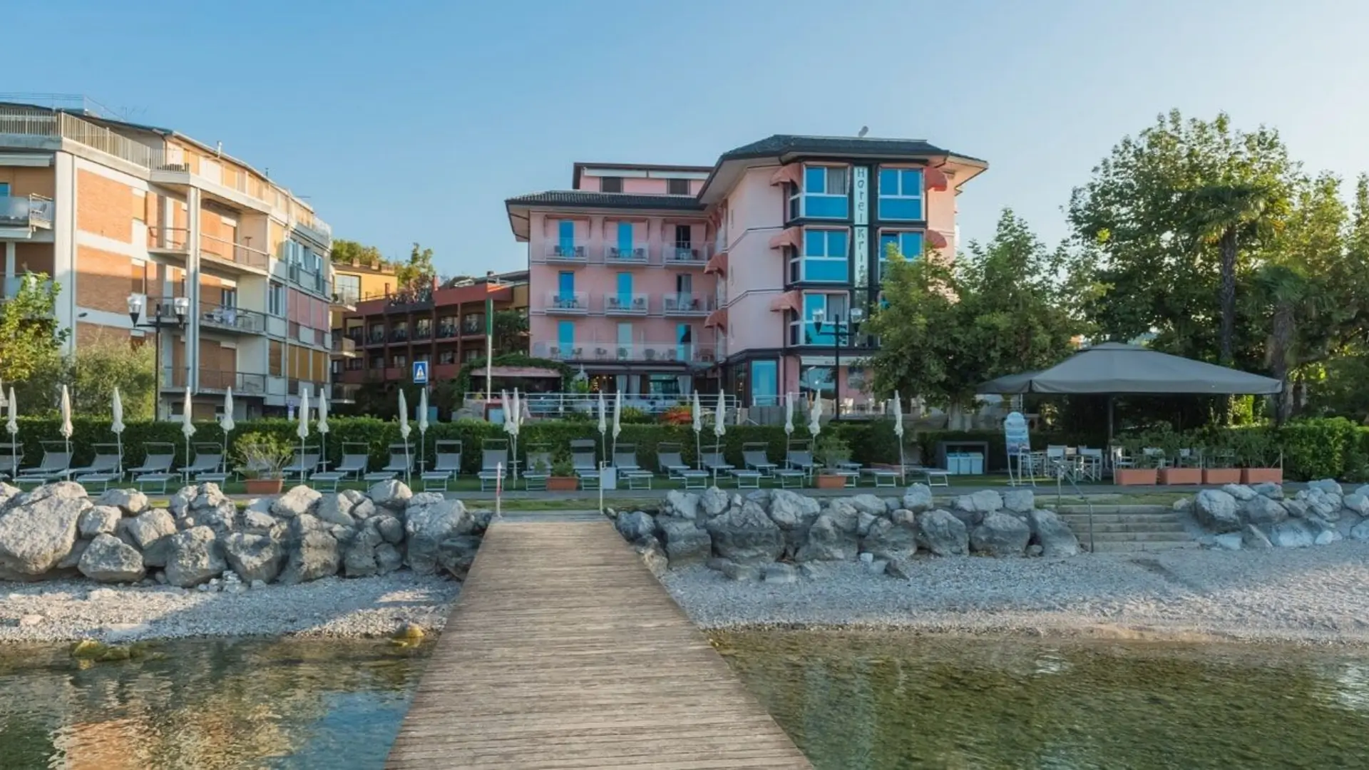Pink lakeside hotel viewed from wooden dock.