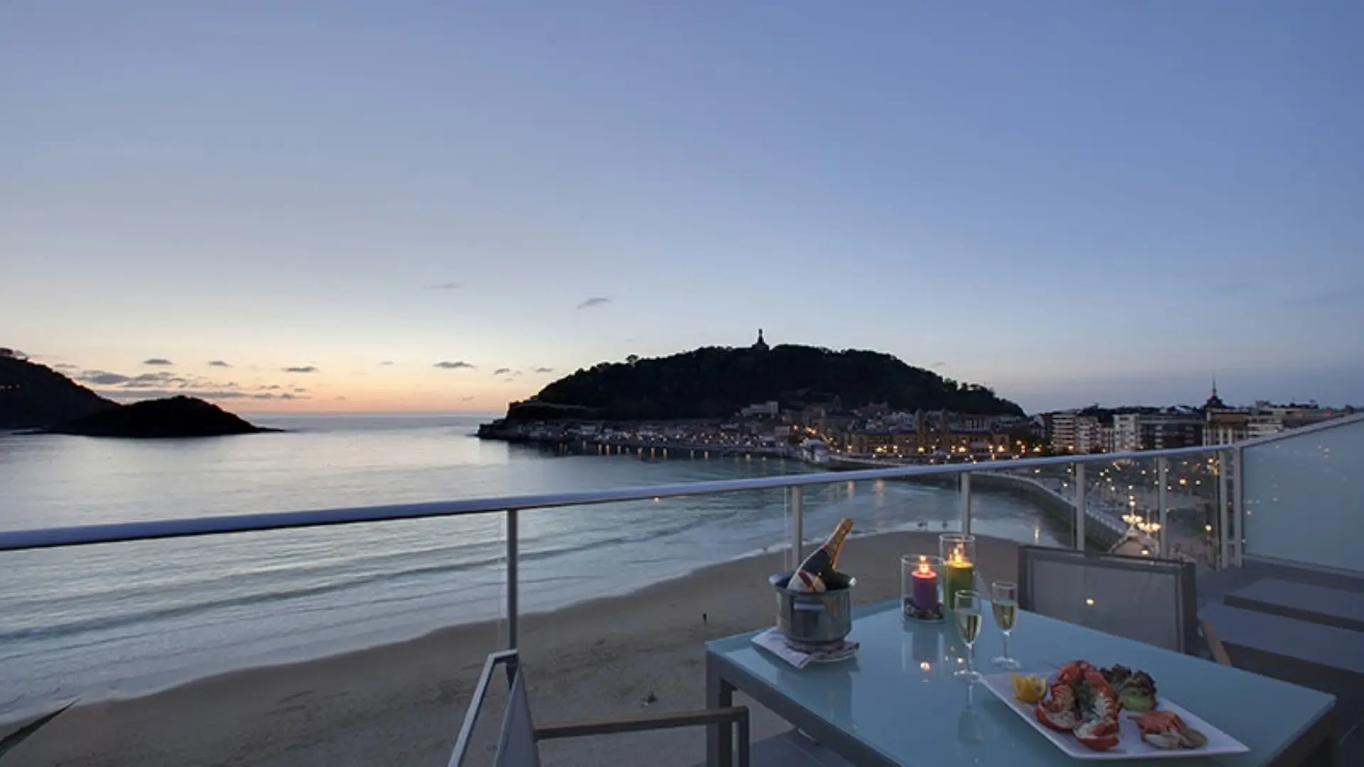 Balcony dining table overlooking bay at sunset.