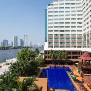 Riverside hotel pool with city skyline view.
