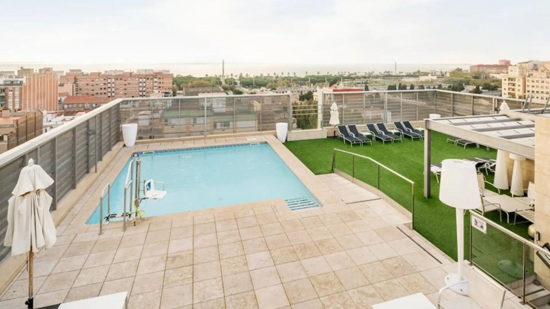 Rooftop pool with hoist and city skyline view.