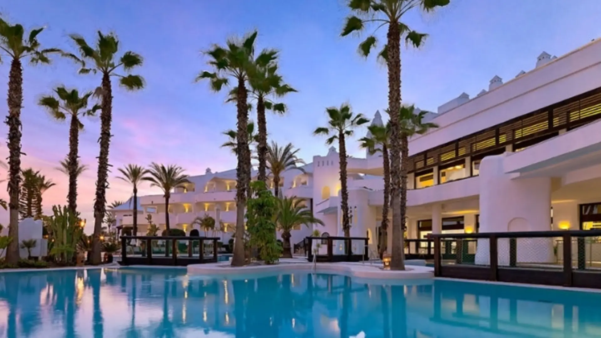 Resort pool with palm trees at dusk.