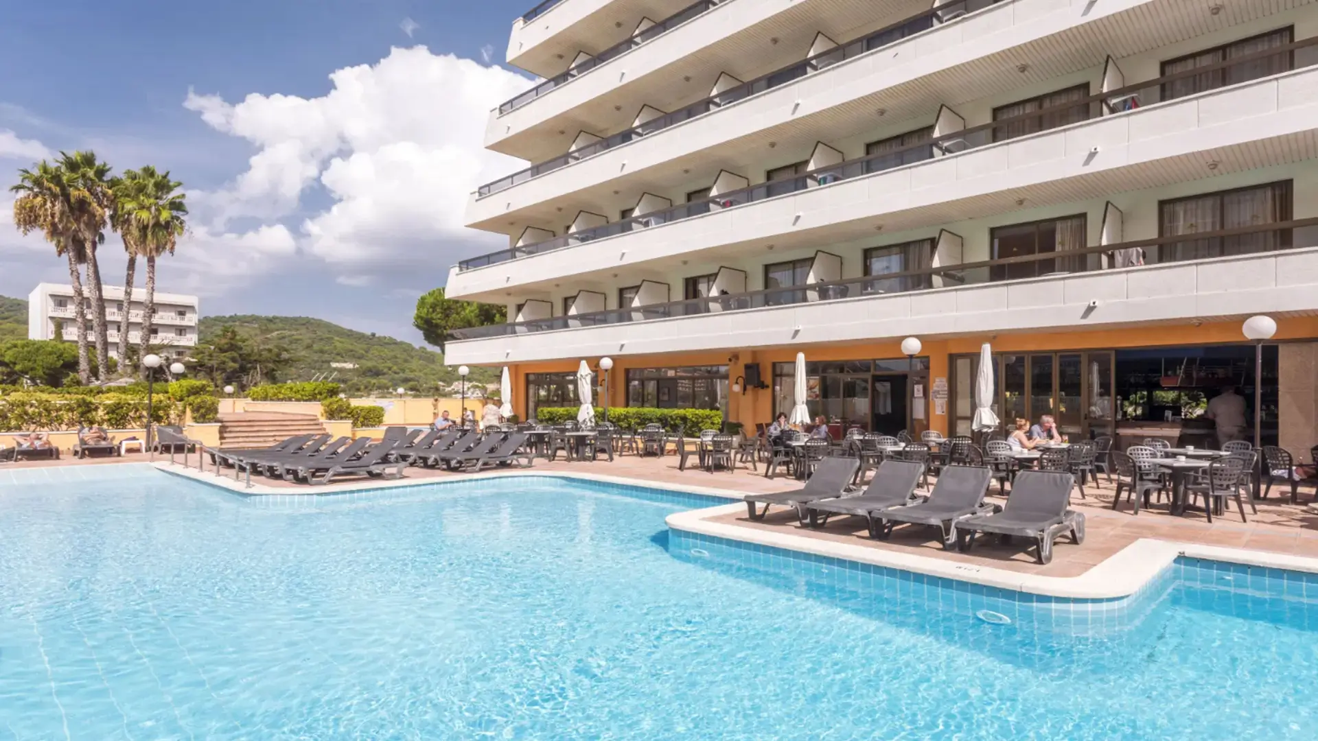 Hotel pool terrace with loungers and dining area.