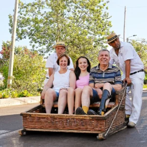 Family riding traditional wicker sledge in Madeira.