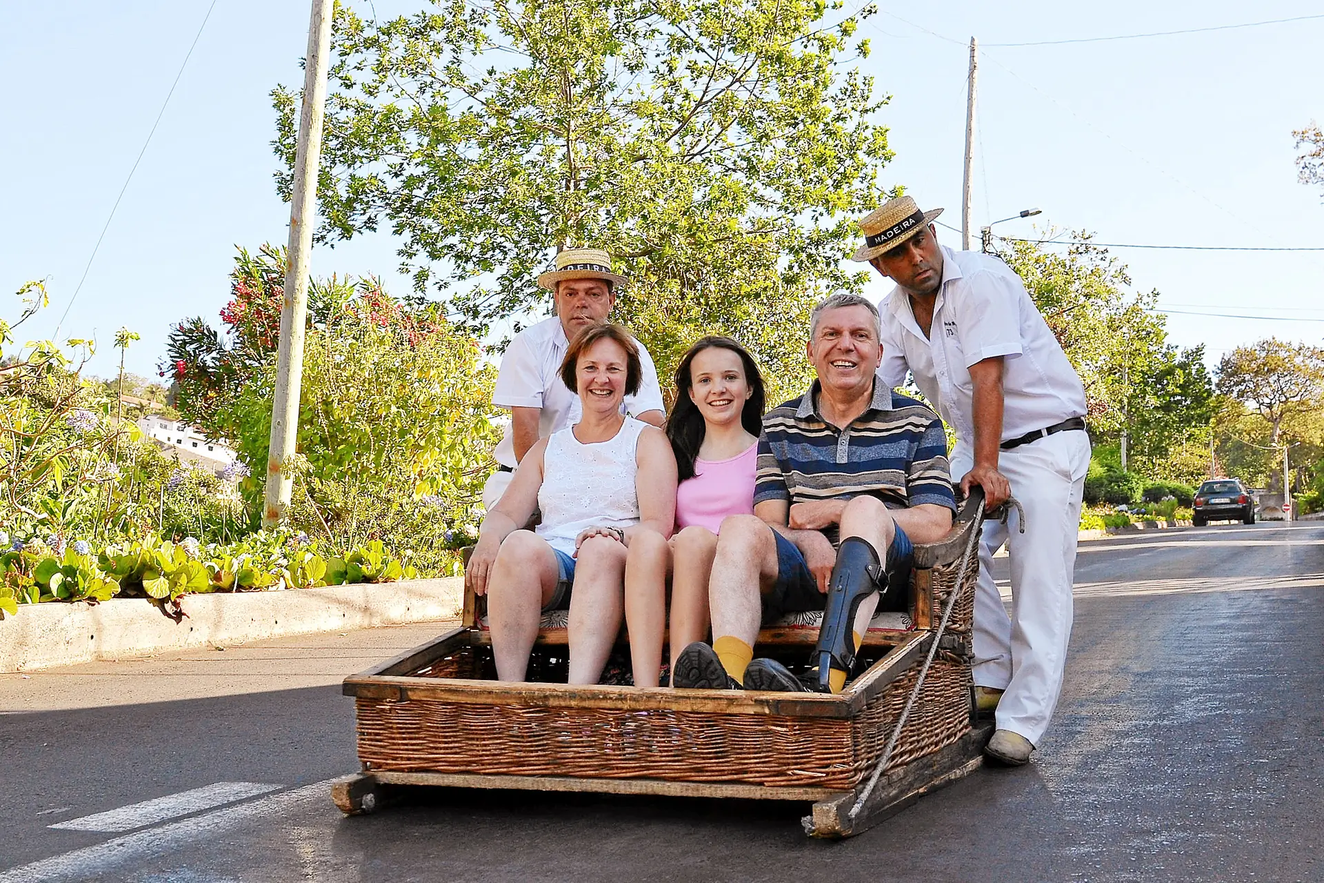 Family riding traditional wicker sledge in Madeira.