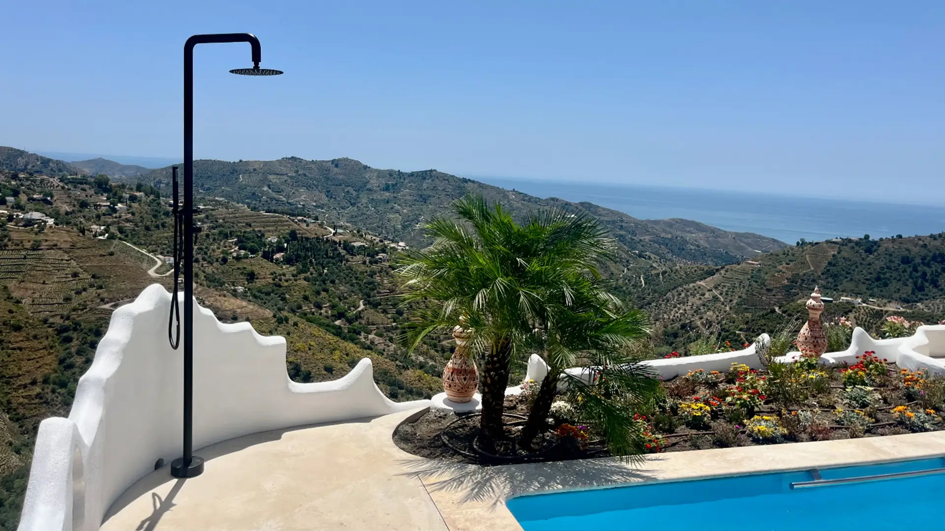 Outdoor shower on terrace overlooking coastal hills.