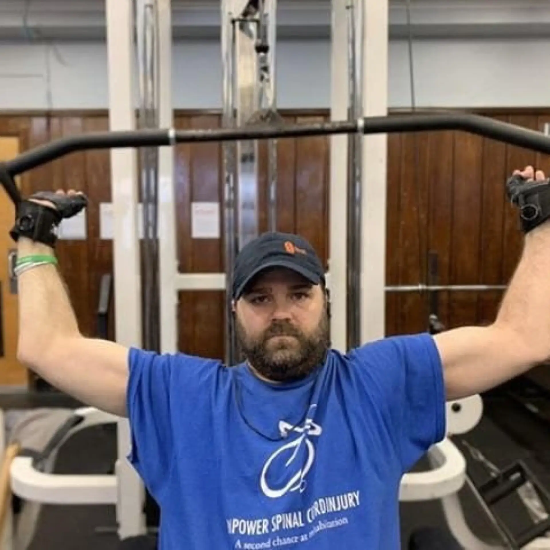 Man using wrist straps to hold a cable machine bar overhead during a lat pulldown exercise.