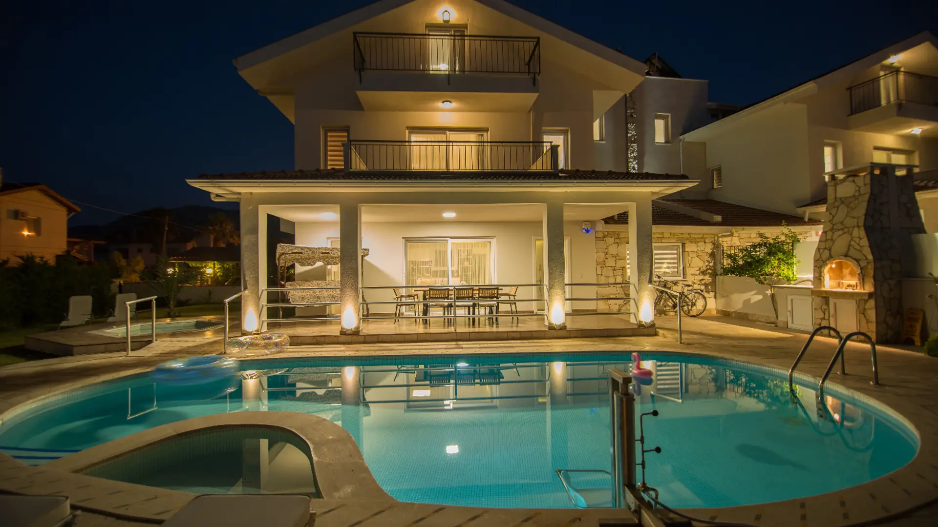Villa pool lit up at night with floats.