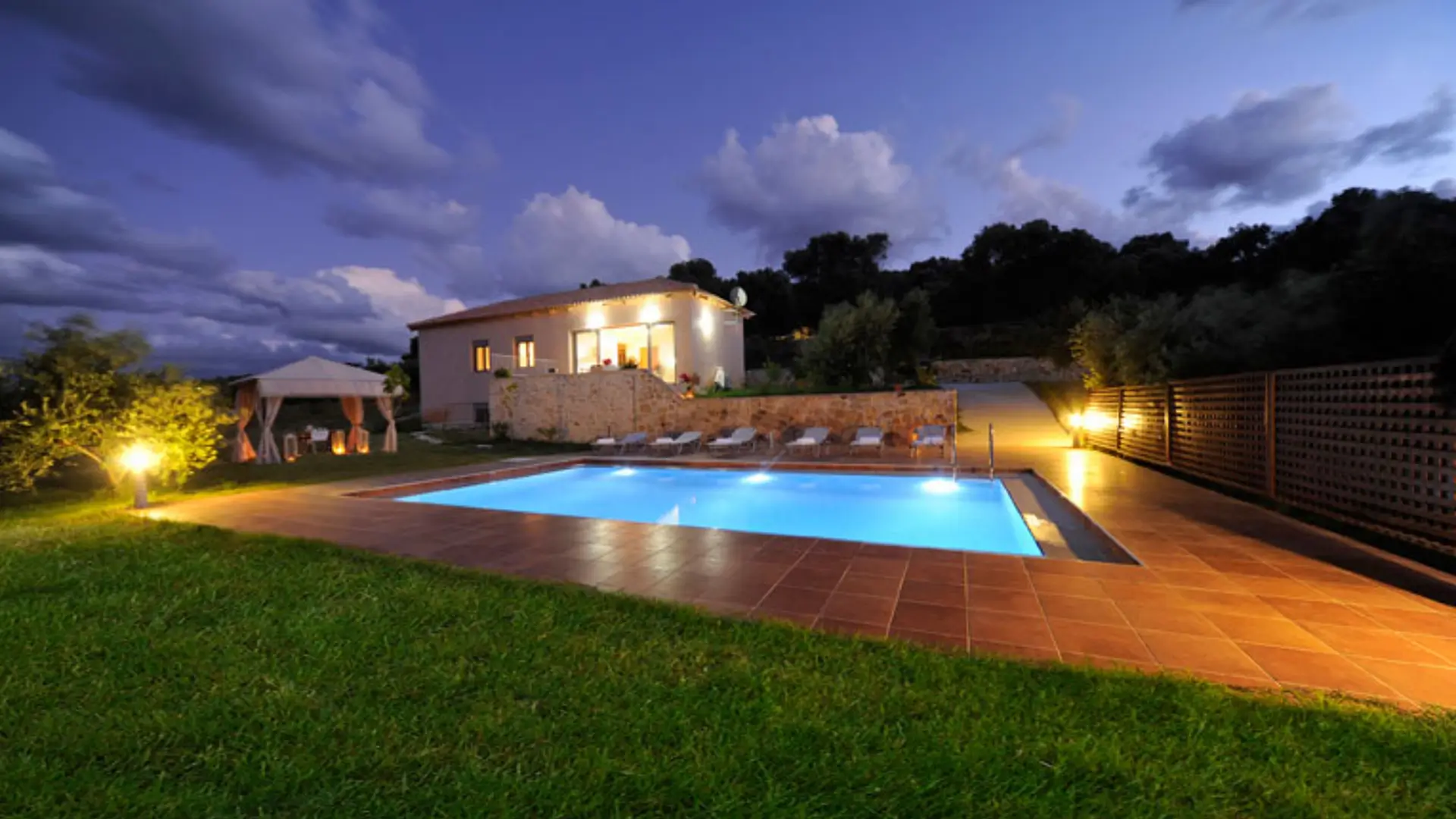 Villa pool and patio lit at dusk.