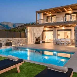 Modern villa pool with loungers at dusk.