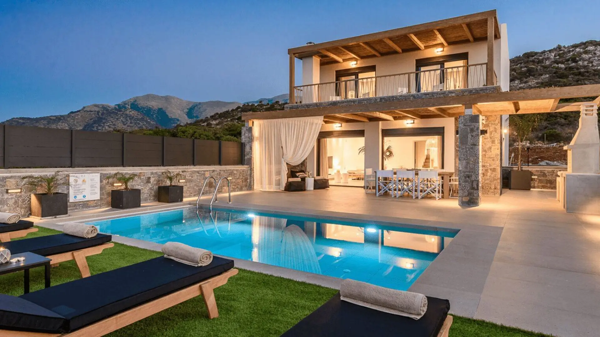 Modern villa pool with loungers at dusk.