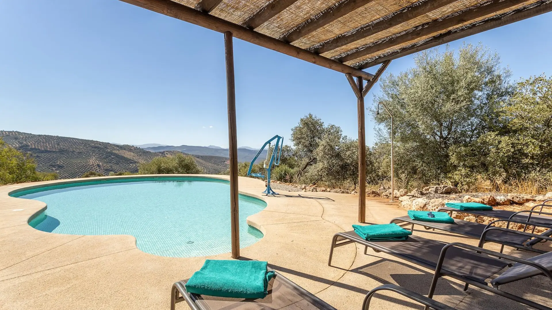 Poolside pergola with pool hoist and mountain view.