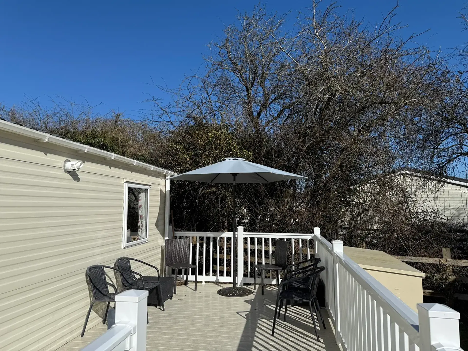 Decking area with rattan chairs and umbrella beside the holiday home.