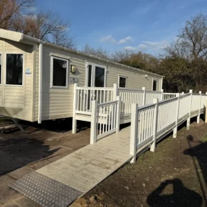 Cream holiday home with a long access ramp and railings alongside.