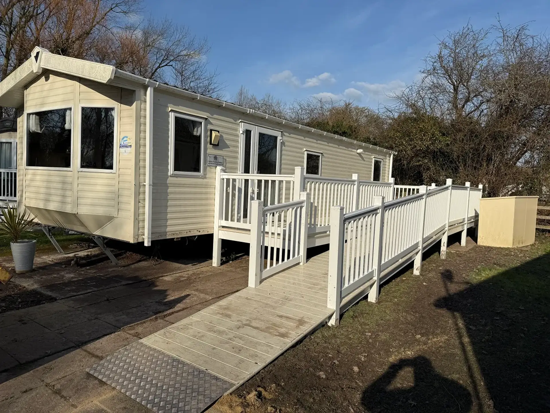 Cream holiday home with a long access ramp and railings alongside.