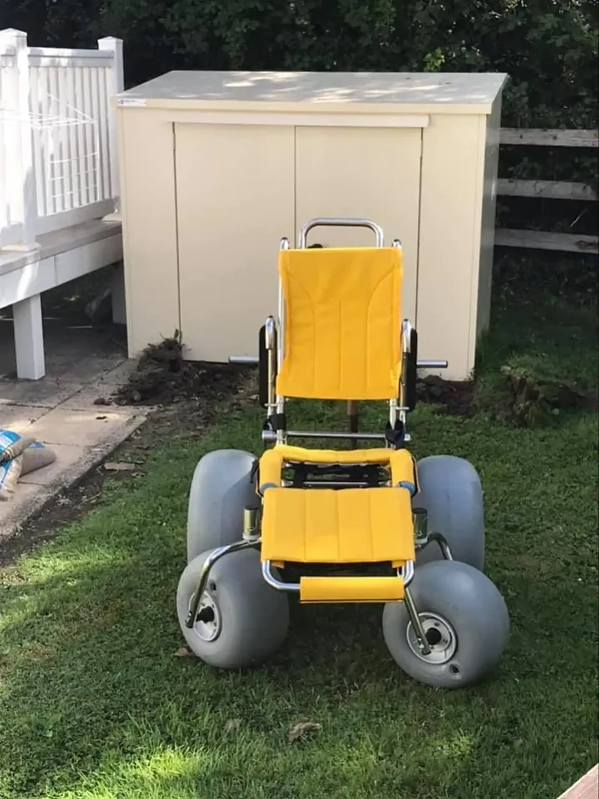 Front view of an all-terrain beach wheelchair with balloon tyres, parked on grass.