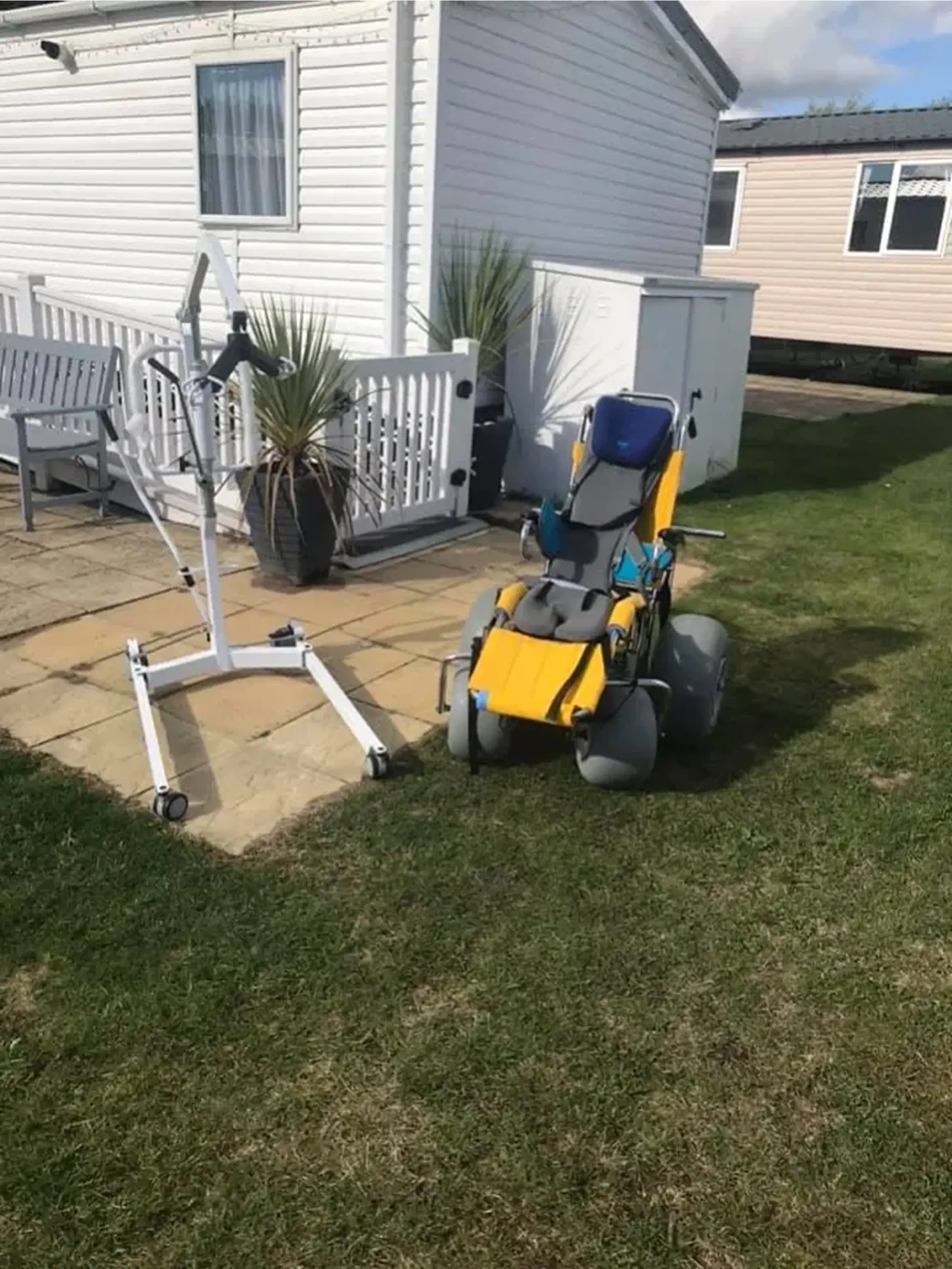 Mobile hoist and an all-terrain wheelchair parked on a patio outside the home.