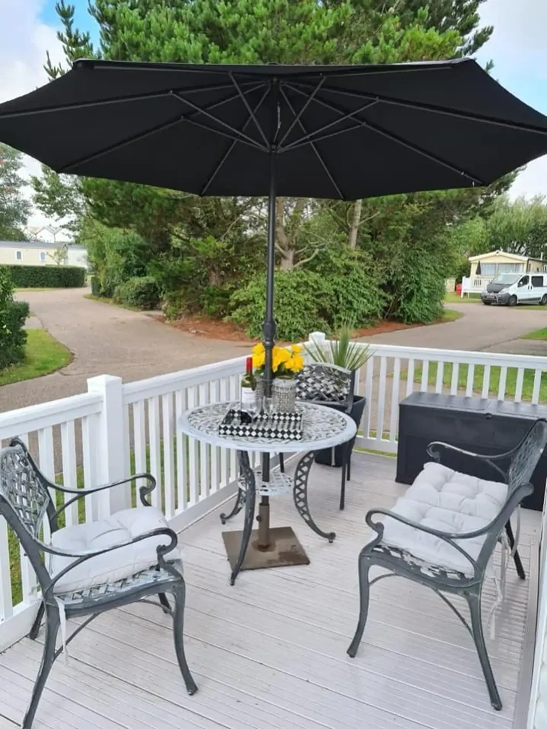 Decking area with patio table, chairs and a black umbrella.