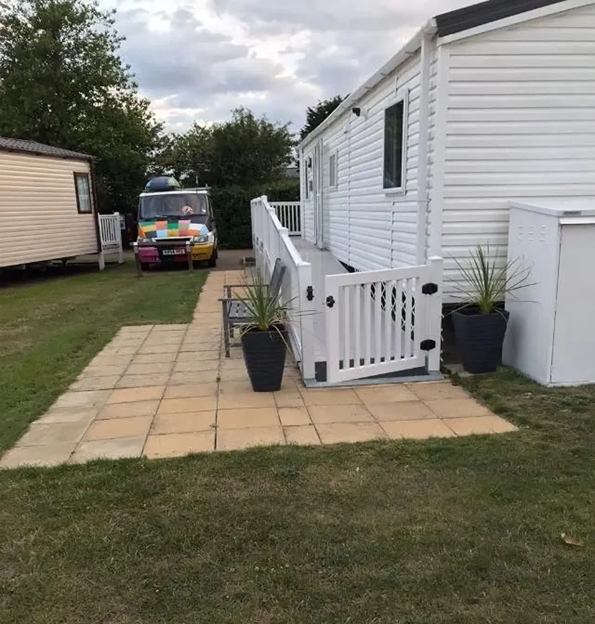 White holiday home with access ramp and gate, parked van alongside.