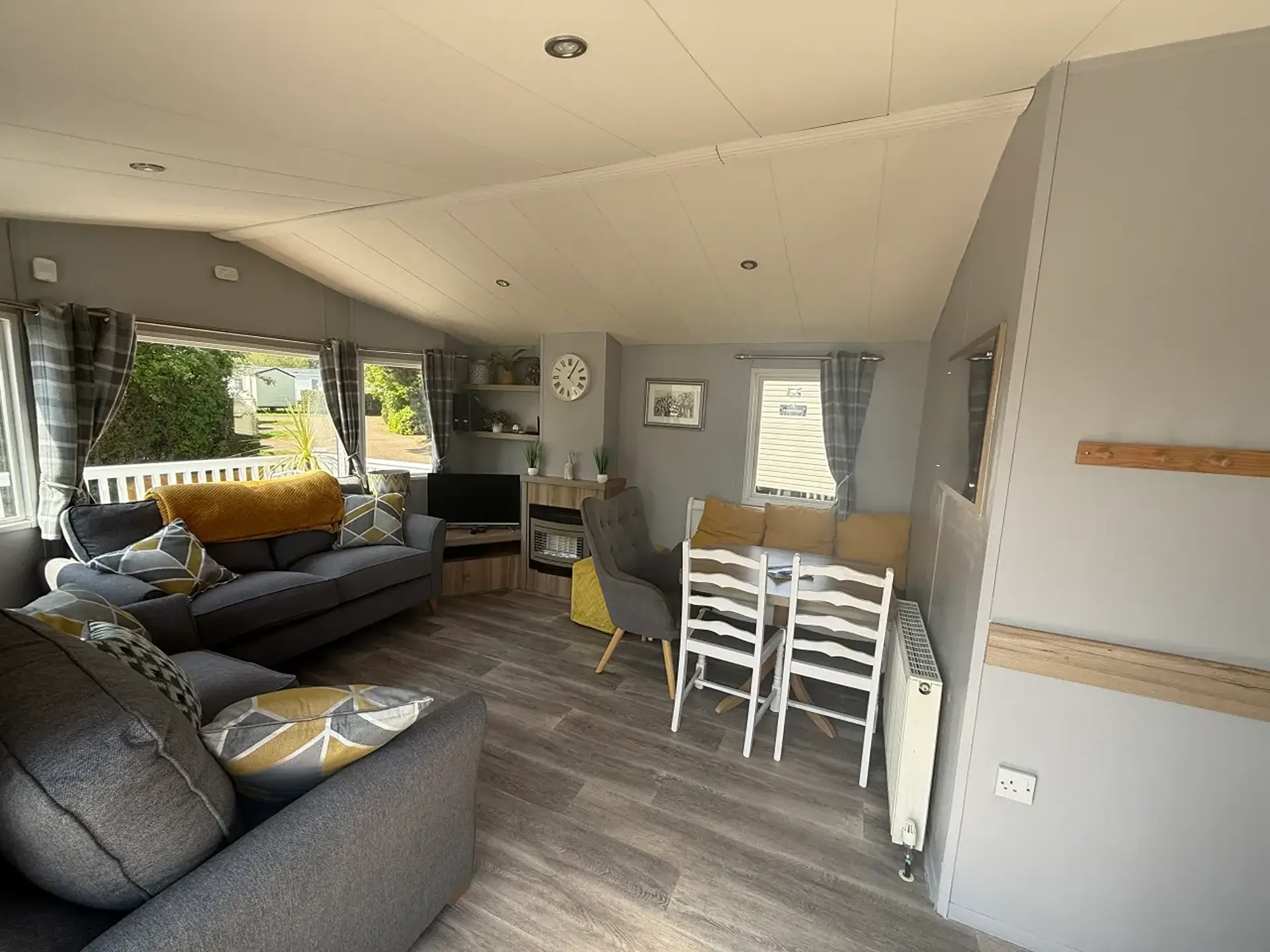 Open-plan lounge with grey corner sofa, dining table and gas fire.