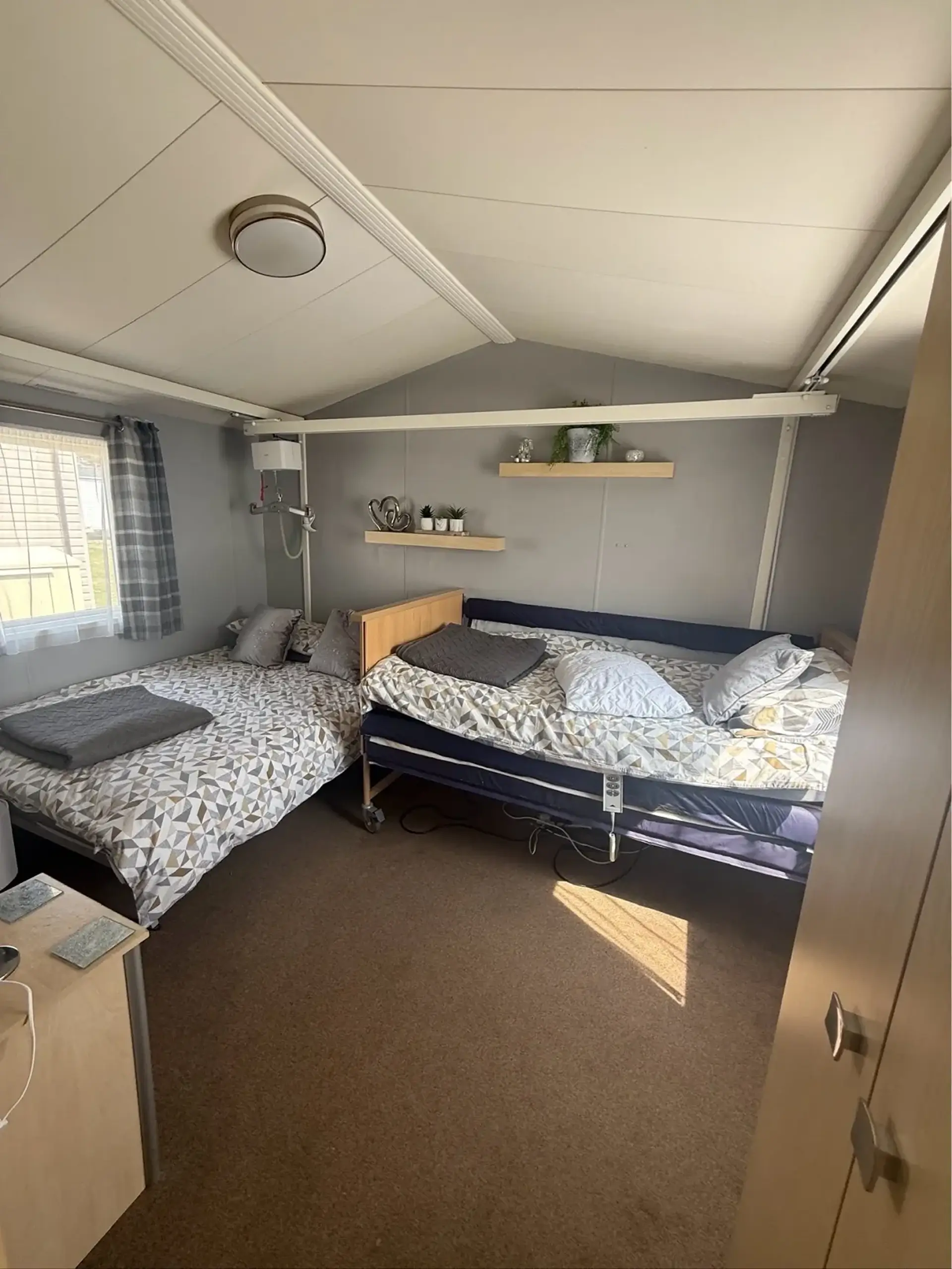 Bedroom with a double bed and adjustable hospital-style bed with ceiling hoist track.