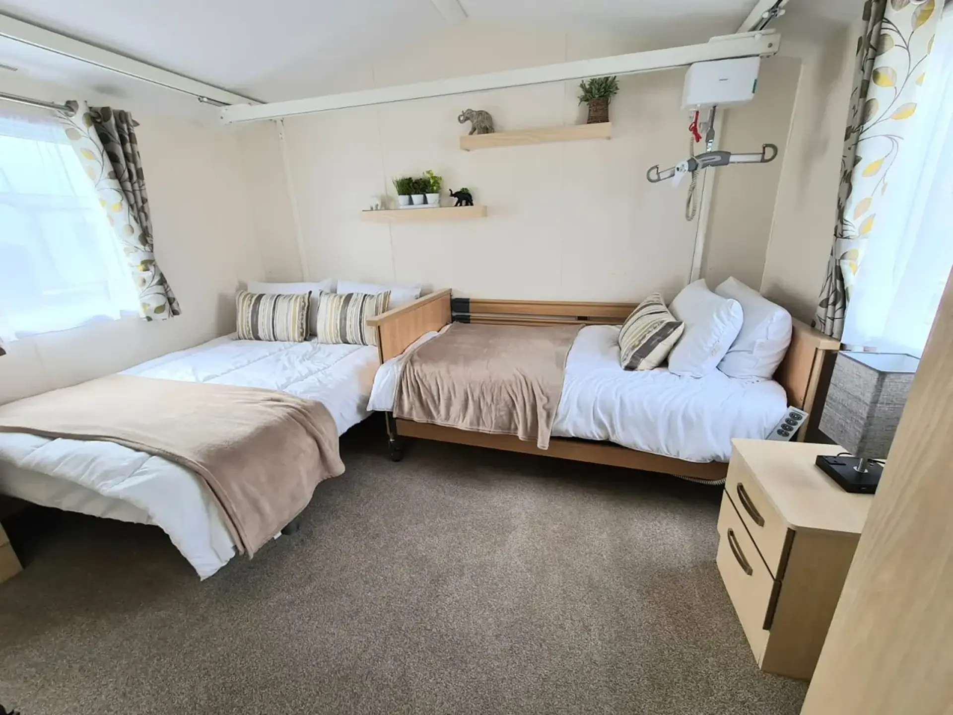 Bedroom with two adjustable beds side by side, ceiling hoist track overhead.