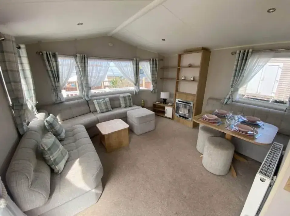 Lounge with grey corner sofa, dining table, and gas fire unit.