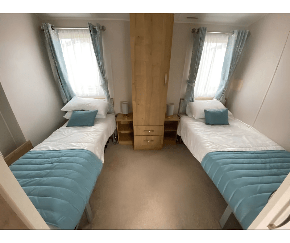 Twin beds either side of a wardrobe with bedside lamps.