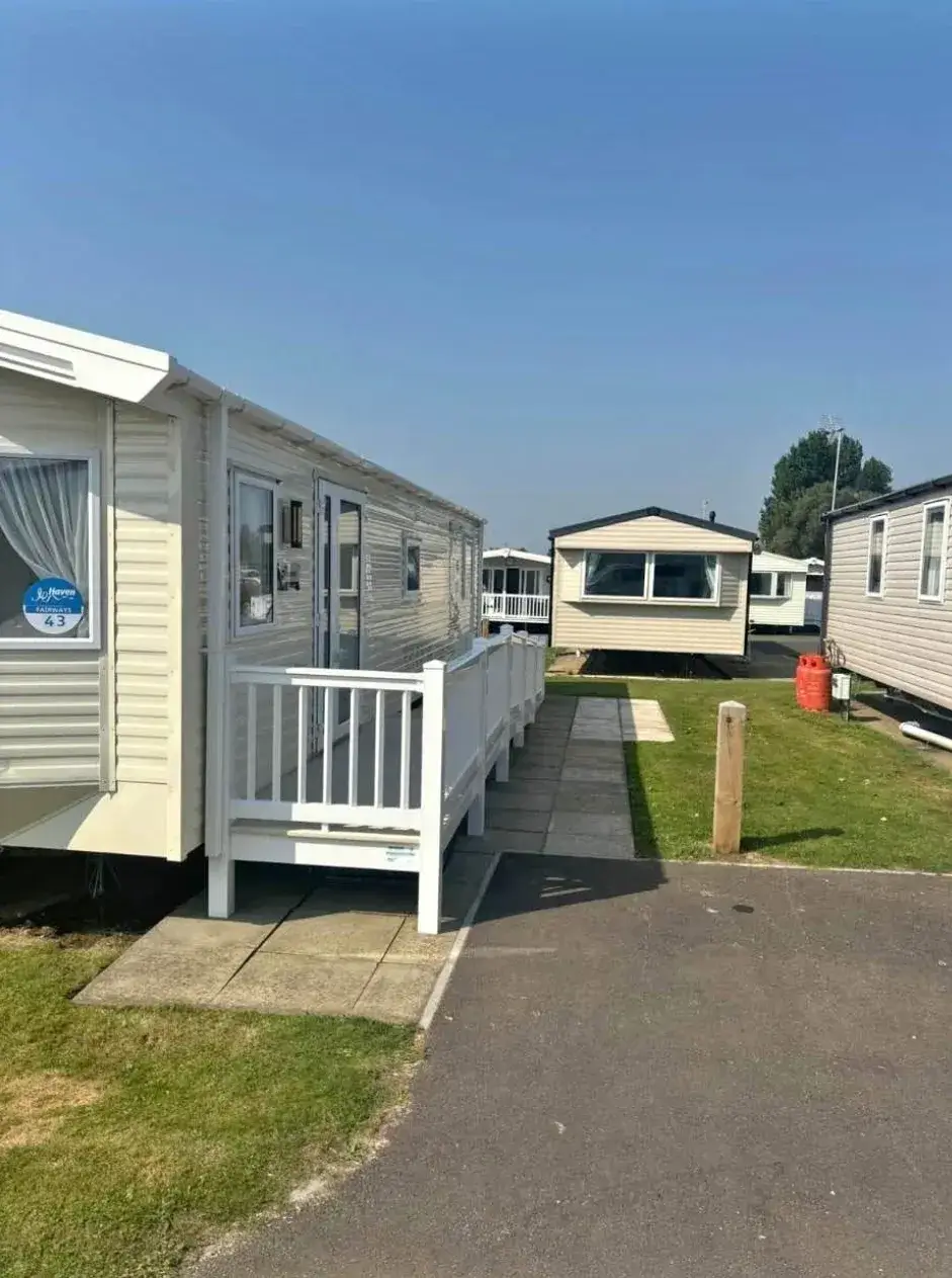 Row of beige static caravans with accessible ramp and pathway.