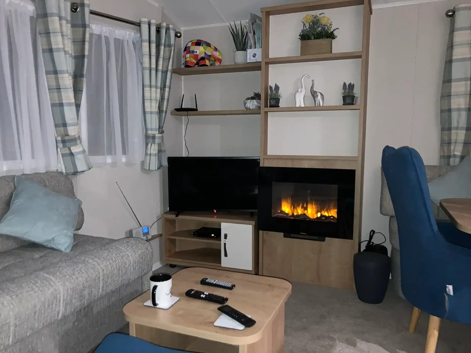 Lounge corner with grey sofa, TV unit, and electric fireplace.