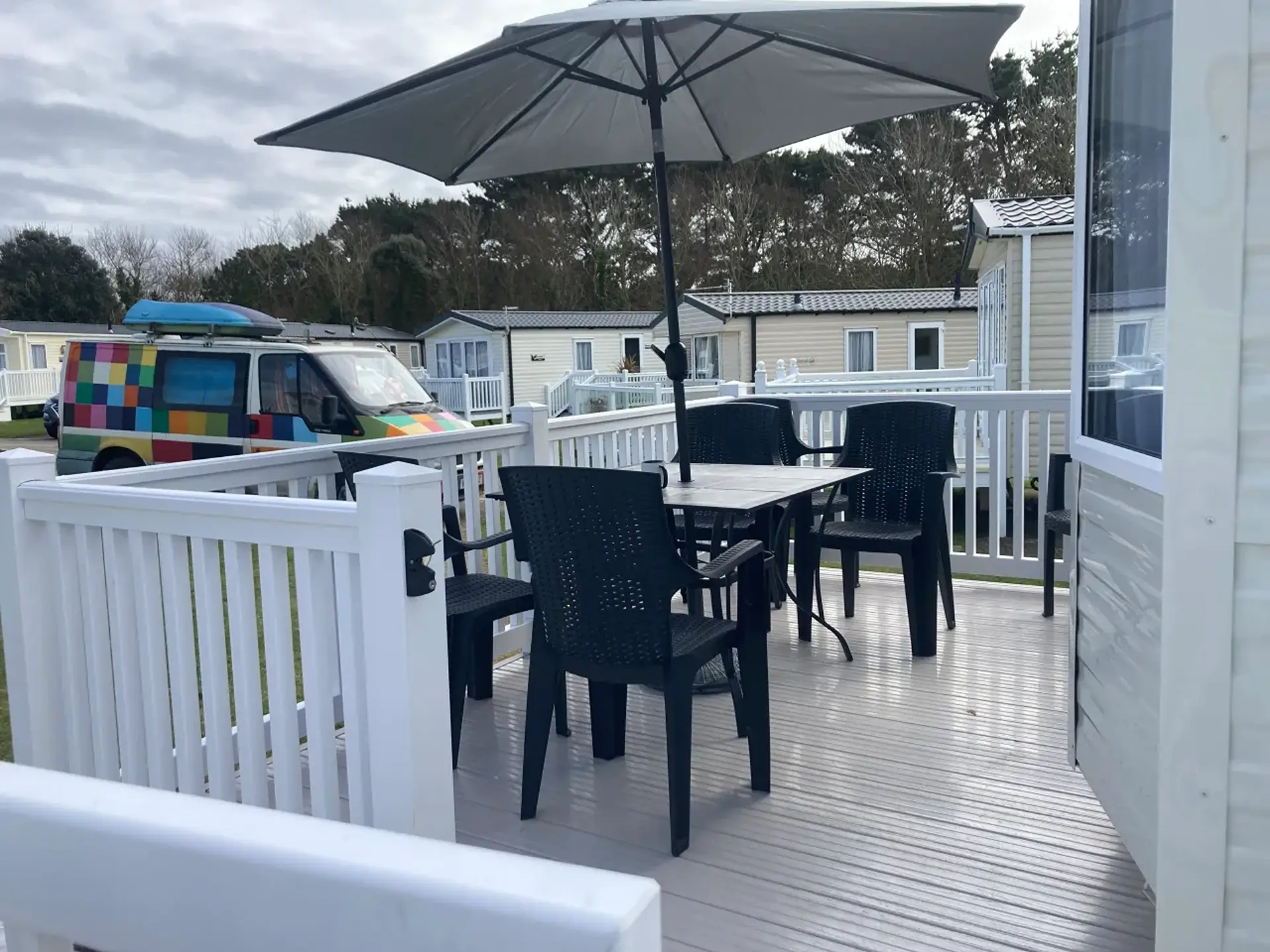 Holiday home decking with table, chairs, and parasol.