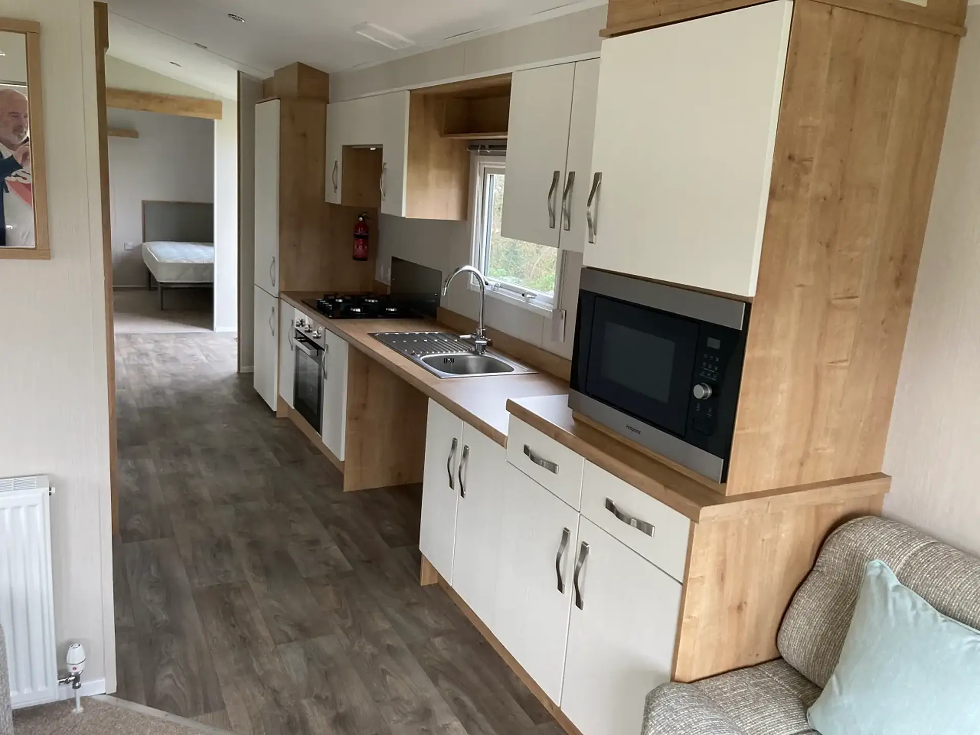 Kitchen with hob, oven, sink, microwave, and view through to bedroom.