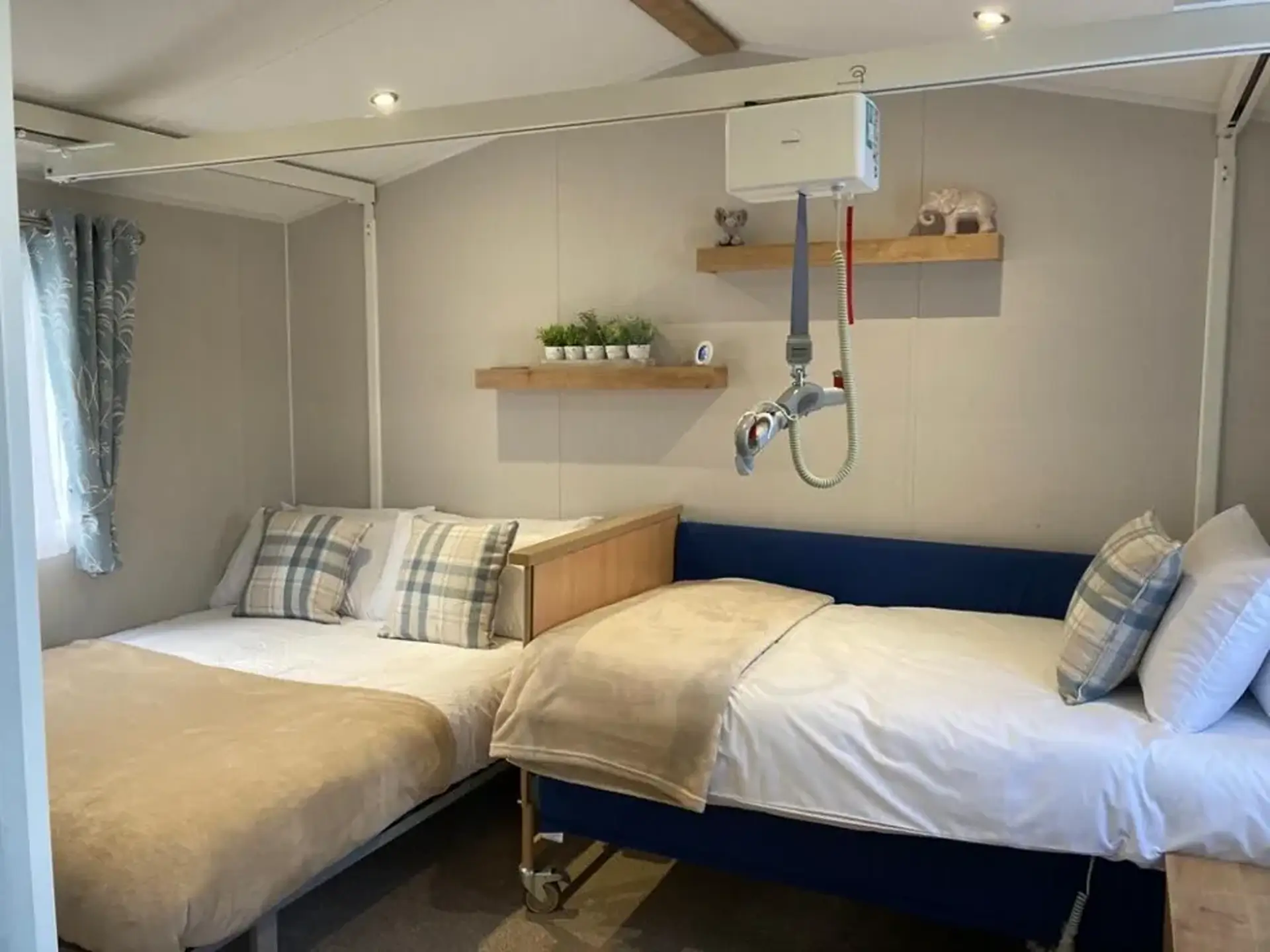 Bedroom with adjustable bed, ceiling hoist, and standard bed alongside.