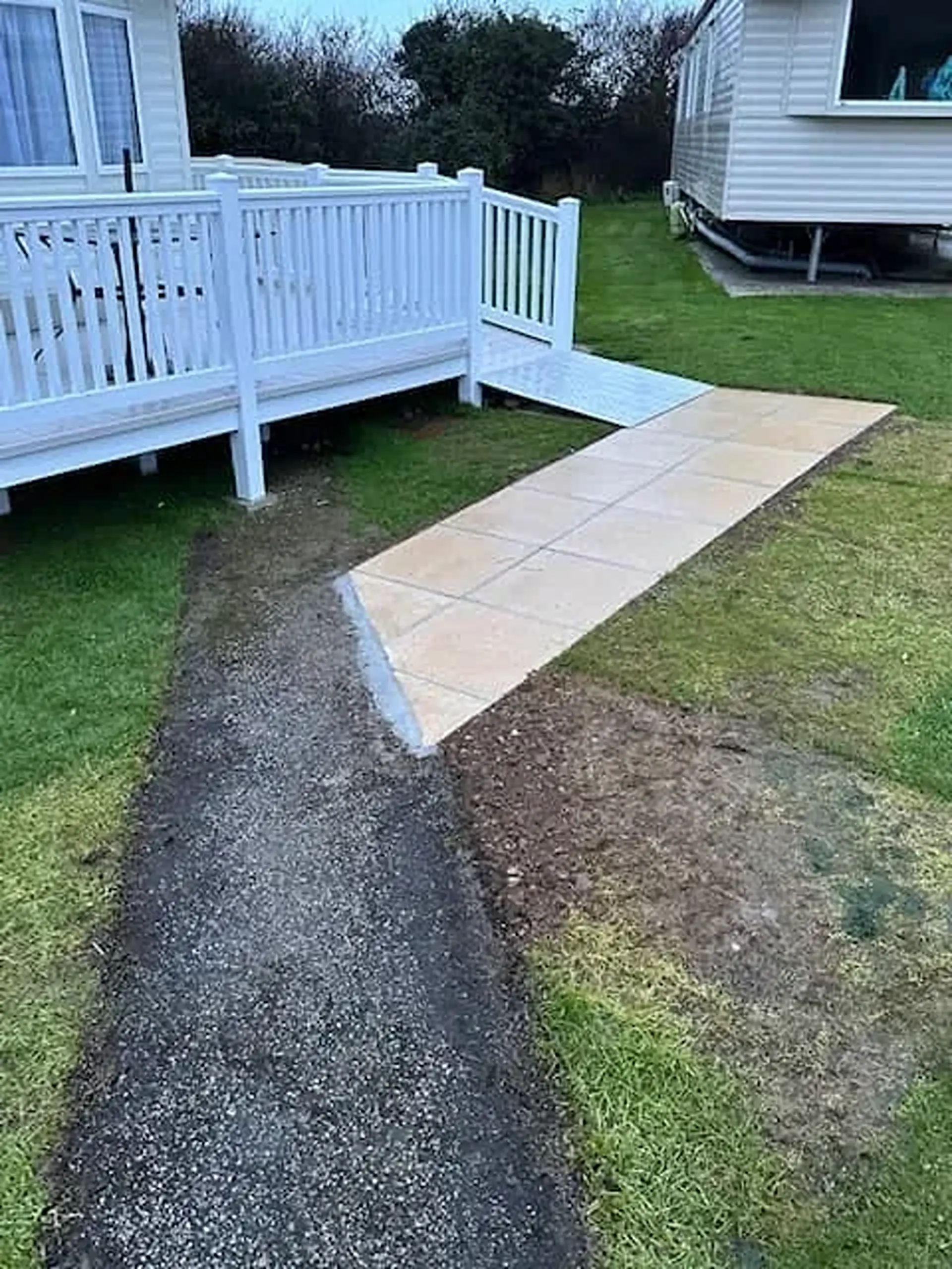Ramp and paved path leading to a caravan's decking.