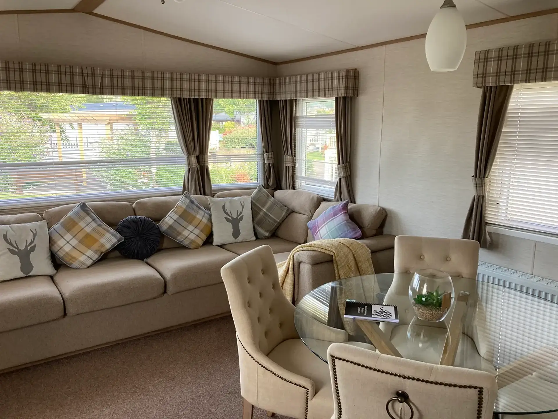 Corner sofa with cushions, dining table, and upholstered chairs by windows.