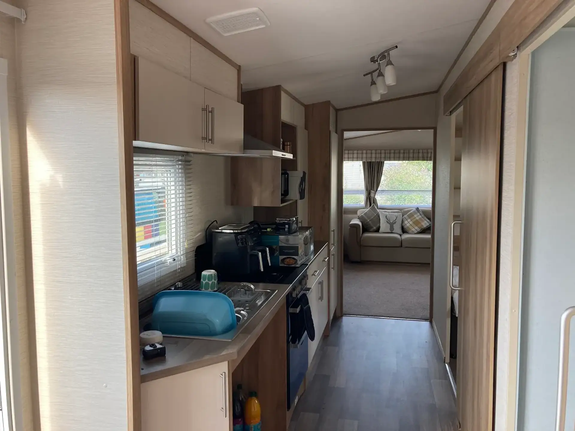 Galley kitchen with hob, sink, and view through to lounge.
