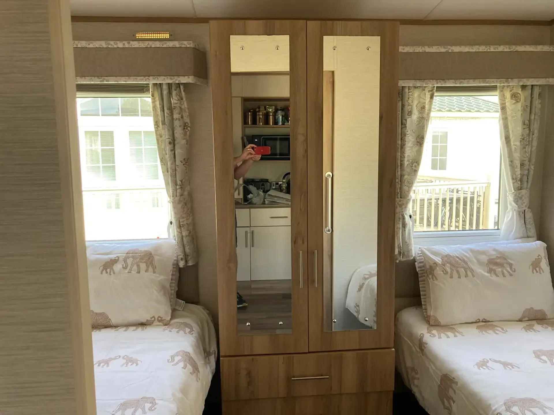 Twin beds either side of a mirrored wardrobe.