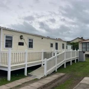 Beige static holiday home with wraparound accessible ramp and railings.