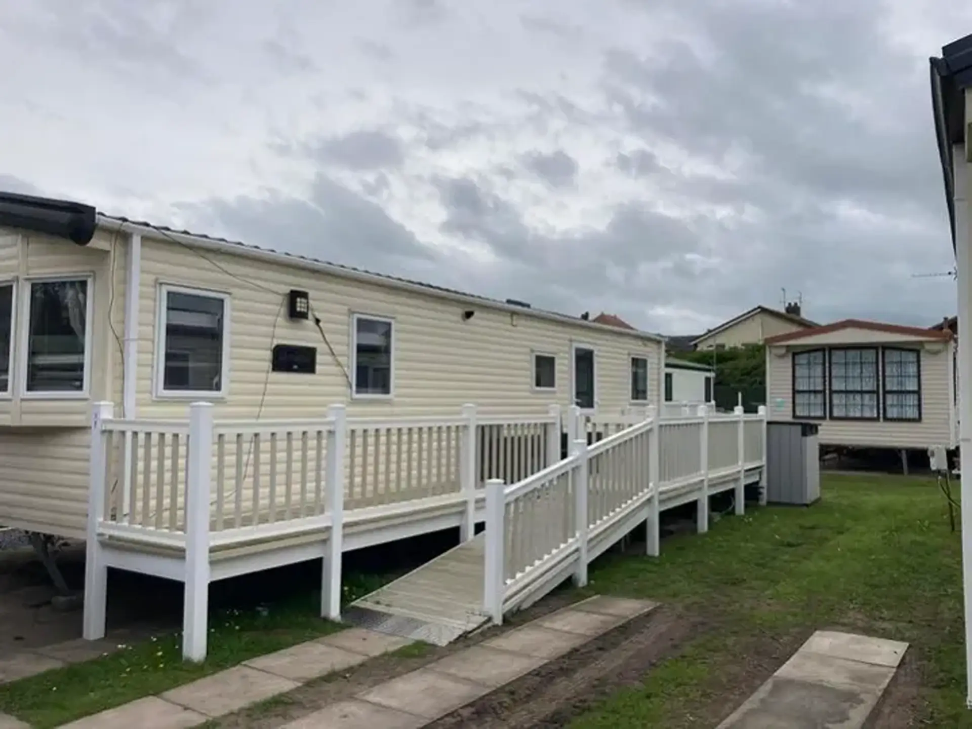 Beige static holiday home with wraparound accessible ramp and railings.