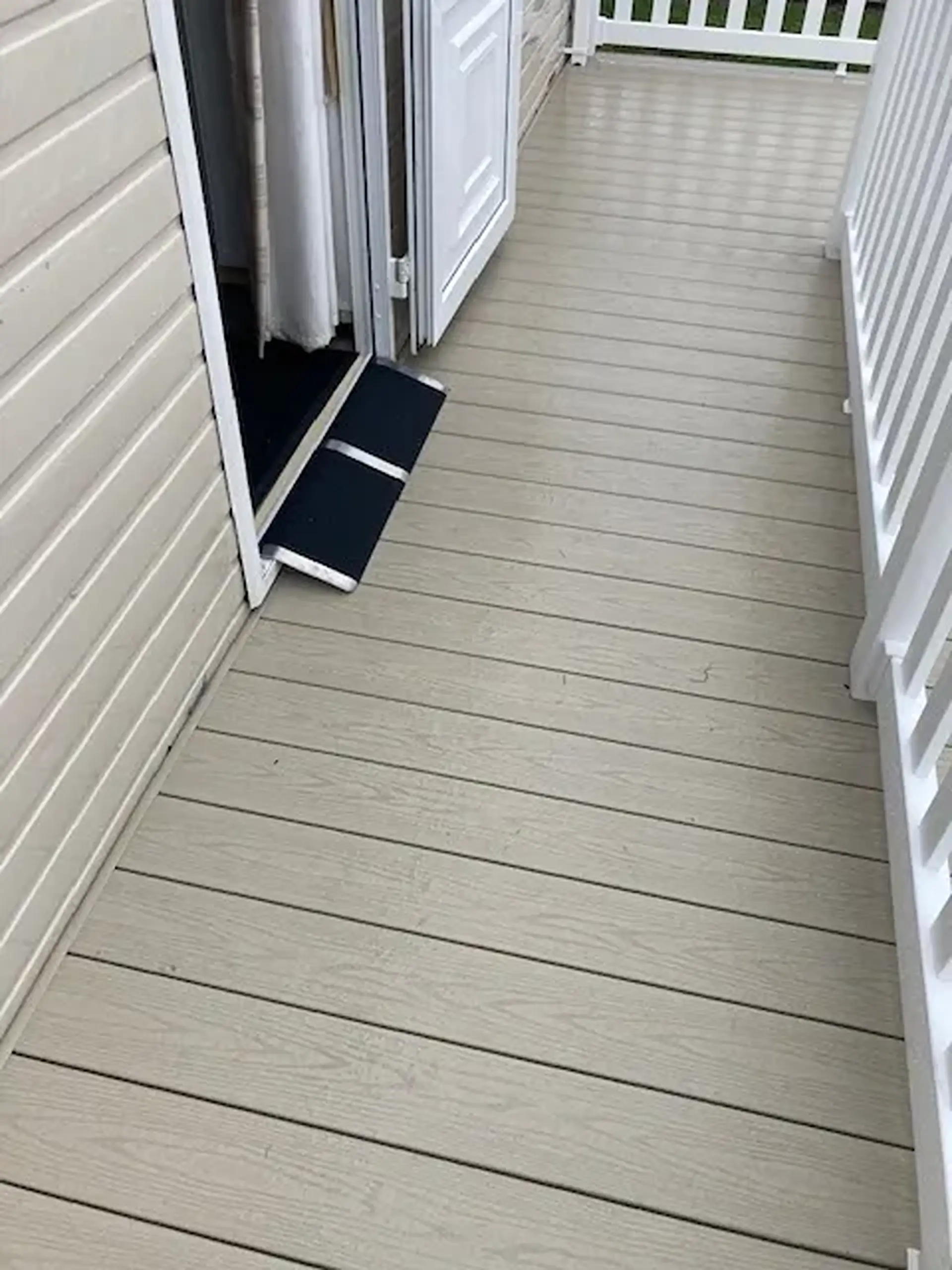 Portable ramp at a caravan's folding doors leading onto decking.