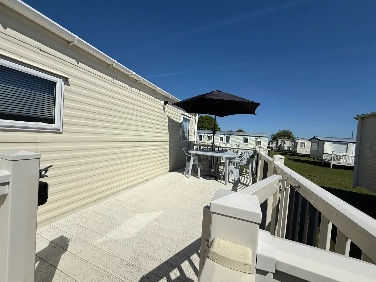 Caravan decking with table, chairs, and parasol.