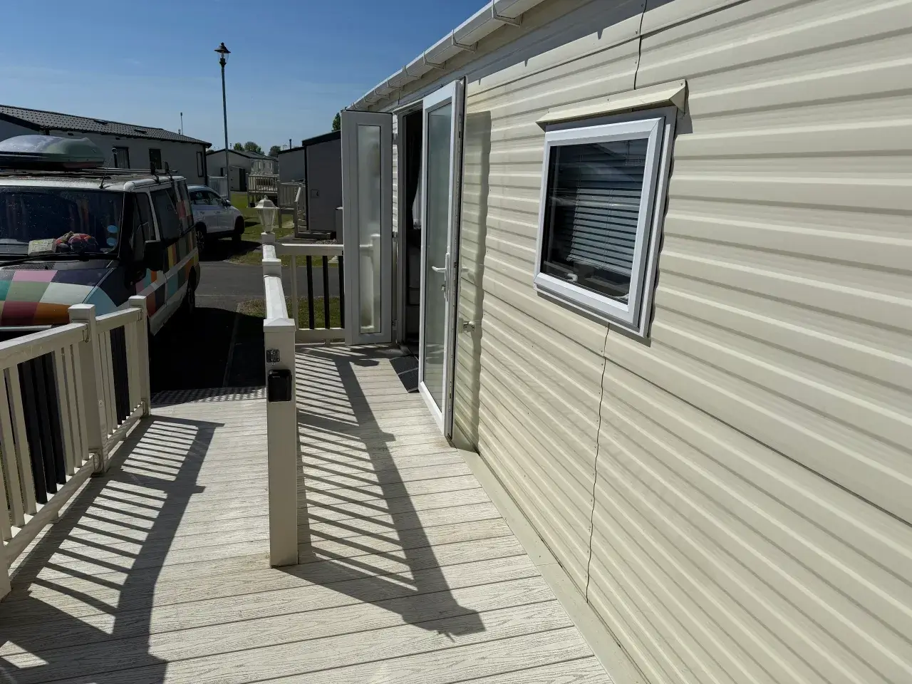 Caravan exterior with open doors leading onto decking.