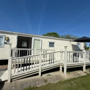 Beige static caravan with long accessible ramp and decking.