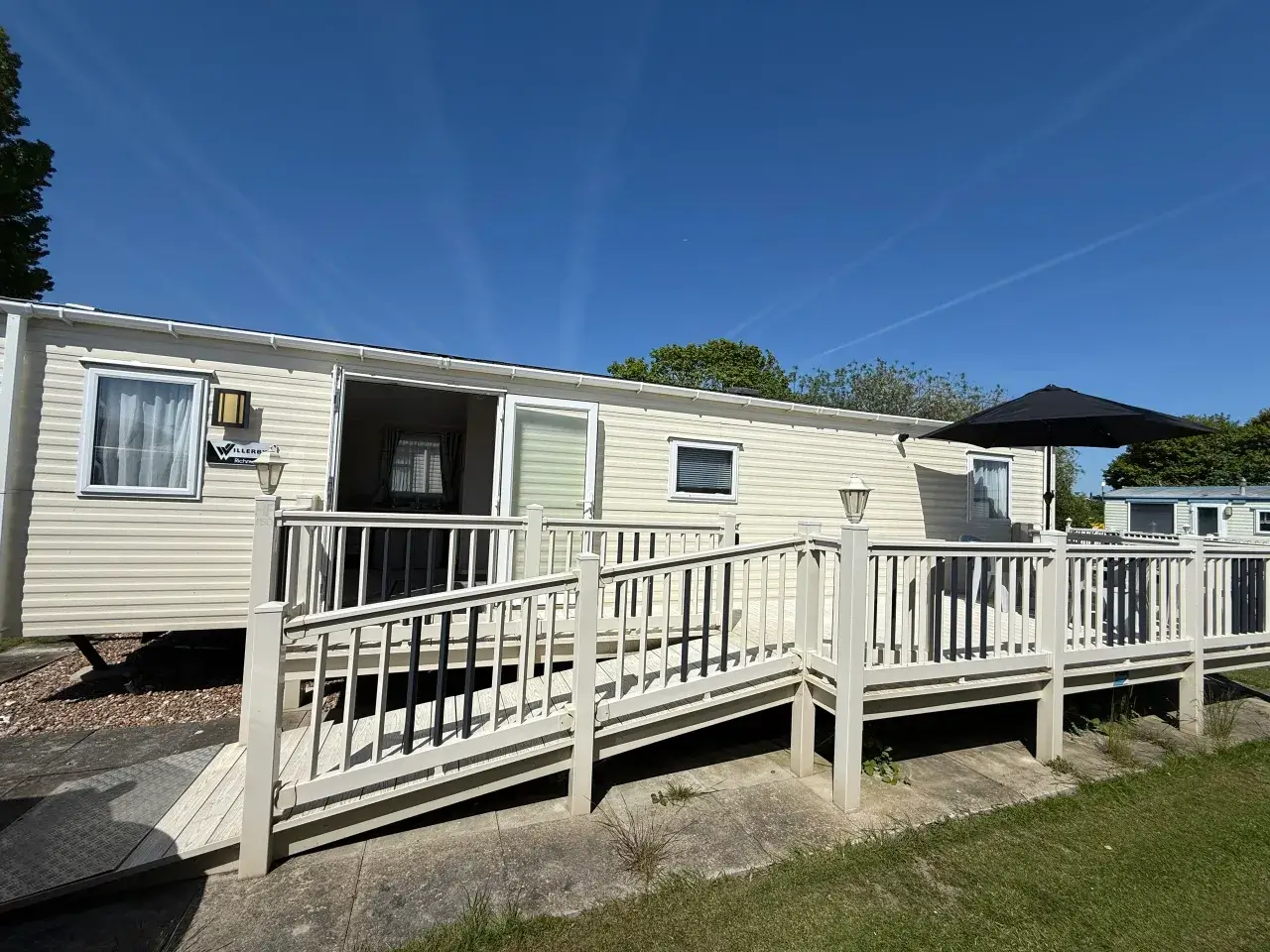 Beige static caravan with long accessible ramp and decking.