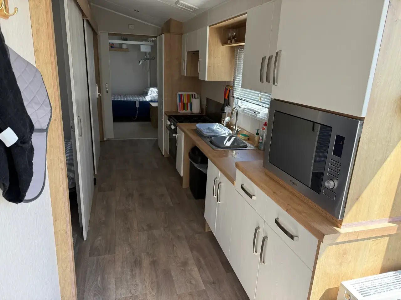 Galley kitchen with hob, sink, microwave, and view to bedroom.